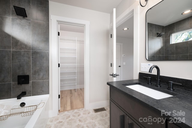 bathroom featuring hardwood / wood-style floors, vanity, and tiled shower / bath