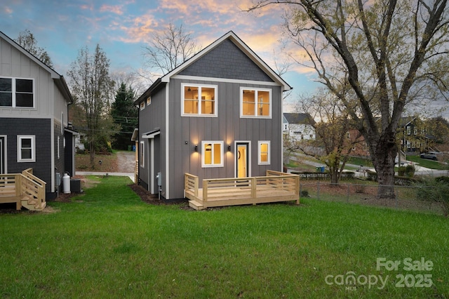 back house at dusk featuring central AC, a lawn, and a deck