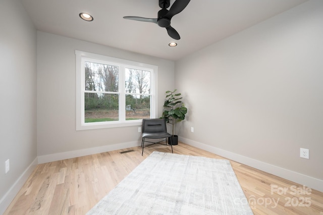 living area with hardwood / wood-style flooring and ceiling fan