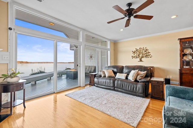 living room featuring ceiling fan, crown molding, a water view, and light wood-type flooring