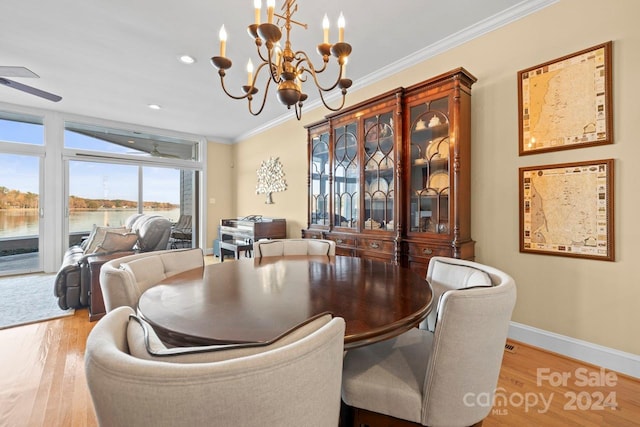 dining room featuring ceiling fan with notable chandelier, light hardwood / wood-style floors, a water view, and crown molding