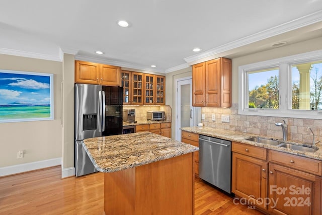 kitchen with tasteful backsplash, stainless steel appliances, sink, a center island, and light hardwood / wood-style floors