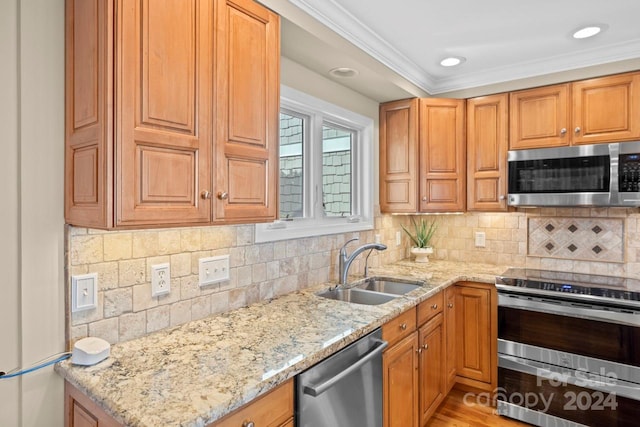 kitchen with sink, light stone counters, crown molding, decorative backsplash, and appliances with stainless steel finishes