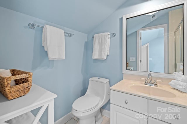 bathroom with tile patterned flooring, vanity, vaulted ceiling, and toilet