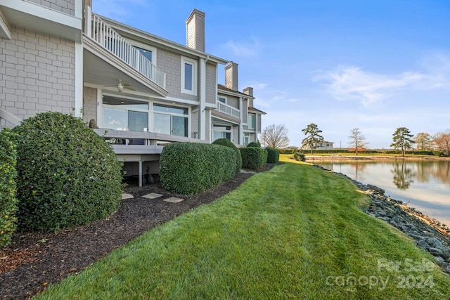 view of yard featuring ceiling fan, a water view, and a balcony