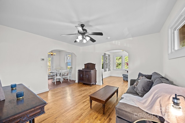 living room featuring ceiling fan with notable chandelier and light wood-type flooring