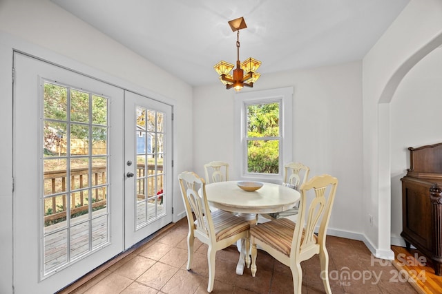 tiled dining area with plenty of natural light, a chandelier, and french doors