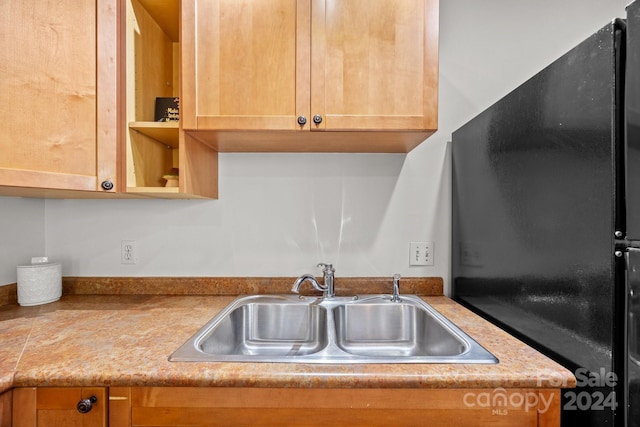 kitchen featuring black fridge and sink