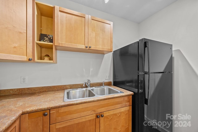 kitchen with black refrigerator, light brown cabinets, and sink