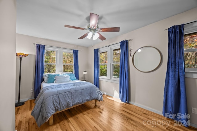 bedroom with ceiling fan, wood-type flooring, and multiple windows