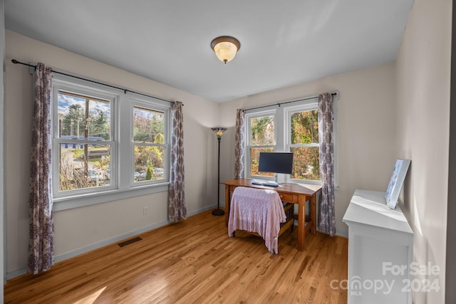 home office with a healthy amount of sunlight and light hardwood / wood-style flooring