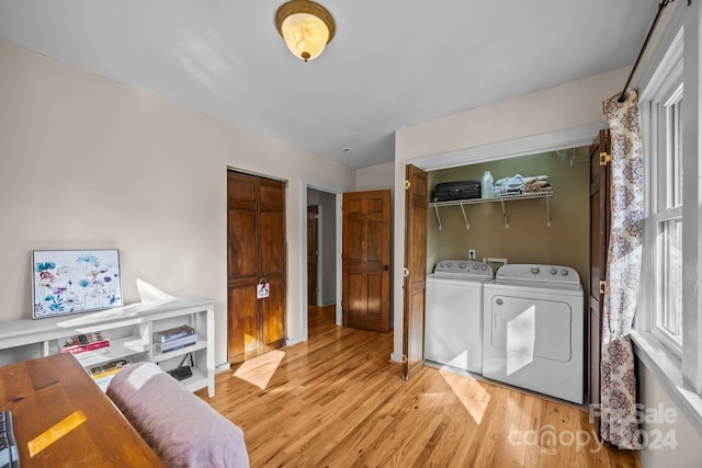 clothes washing area with light hardwood / wood-style floors and washing machine and dryer