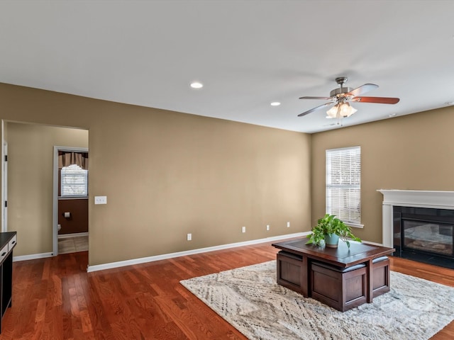 living room with a wealth of natural light, a fireplace, ceiling fan, and dark hardwood / wood-style floors