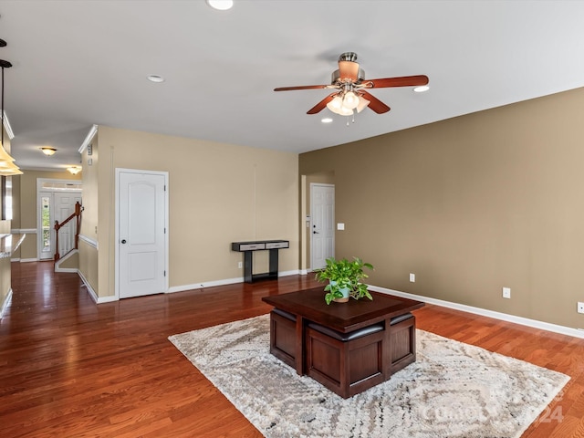 living room featuring ceiling fan and dark wood-type flooring