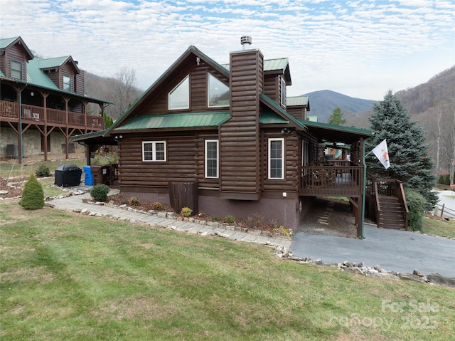 view of side of home featuring a mountain view and a lawn