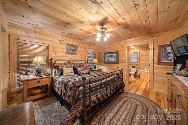 bedroom featuring wood ceiling, ensuite bath, light hardwood / wood-style floors, and wood walls