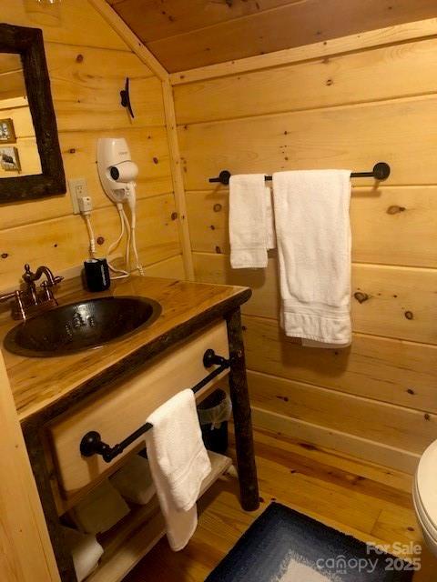 bathroom with vanity, toilet, hardwood / wood-style floors, and wood walls