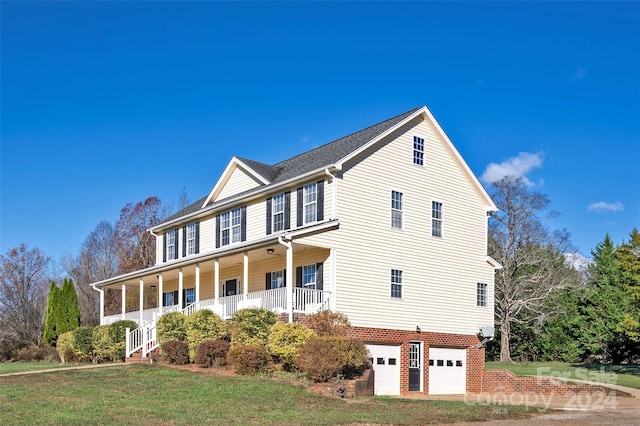 view of front of property with covered porch, a garage, and a front yard