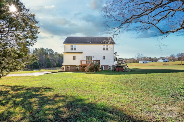 back of property with a wooden deck and a lawn