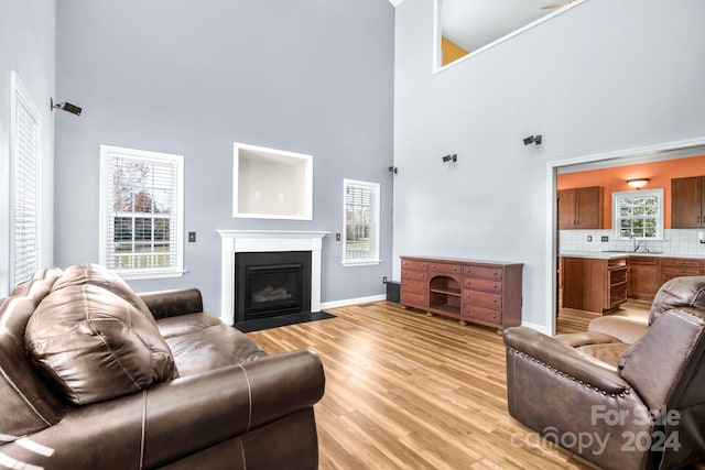 living room featuring sink, a towering ceiling, and light hardwood / wood-style floors