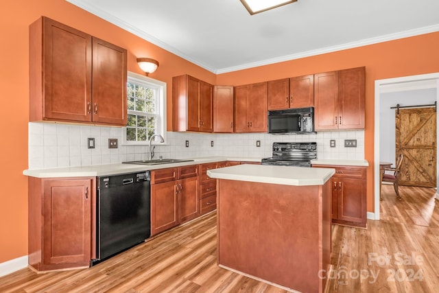 kitchen with sink, black appliances, a barn door, light hardwood / wood-style flooring, and a center island