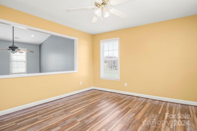 empty room featuring wood-type flooring, a wealth of natural light, and ceiling fan
