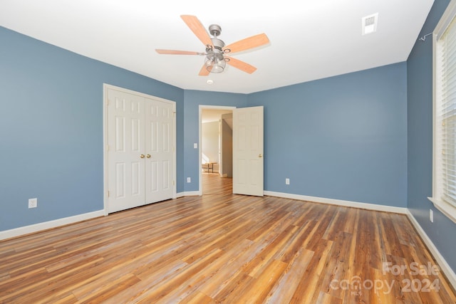 unfurnished bedroom with wood-type flooring, a closet, and ceiling fan