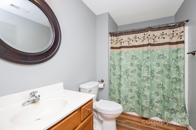 bathroom with a shower with shower curtain, wood-type flooring, vanity, and toilet