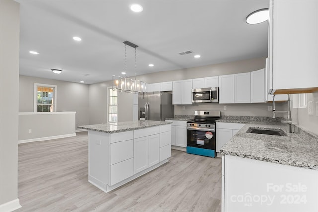 kitchen with a center island, stainless steel appliances, white cabinetry, and hanging light fixtures