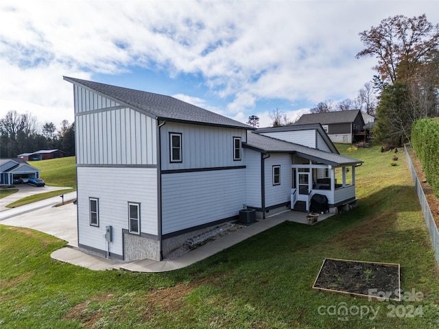 back of house with central AC unit and a lawn