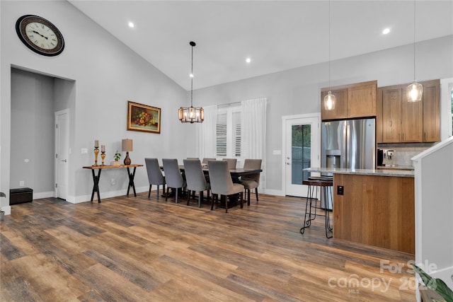 dining room featuring dark hardwood / wood-style flooring, high vaulted ceiling, and a chandelier