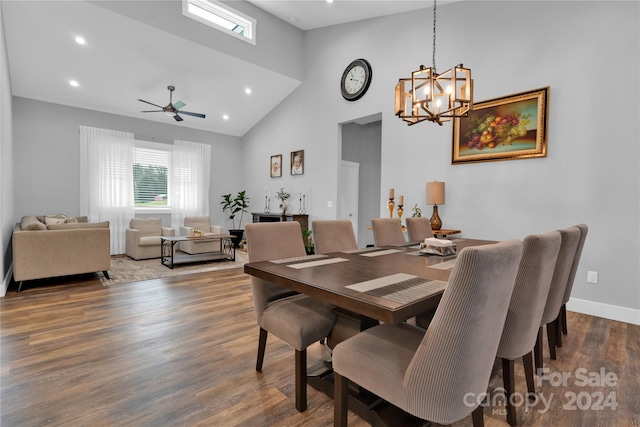 dining room with ceiling fan with notable chandelier, dark hardwood / wood-style flooring, and high vaulted ceiling