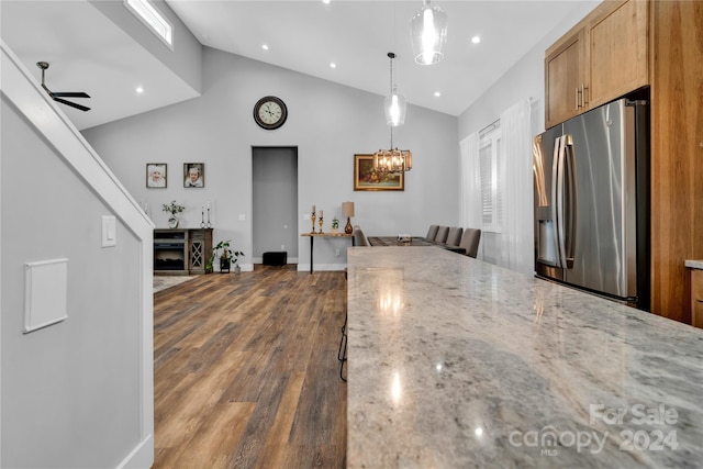 kitchen with stainless steel fridge with ice dispenser, pendant lighting, light stone counters, and dark wood-type flooring