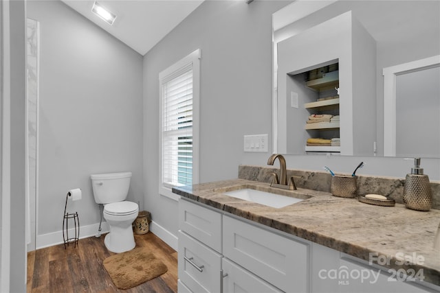 bathroom featuring vanity, hardwood / wood-style flooring, toilet, and lofted ceiling