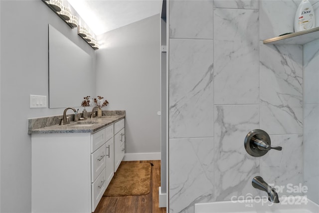 bathroom featuring hardwood / wood-style flooring, vanity, and tiled shower / bath