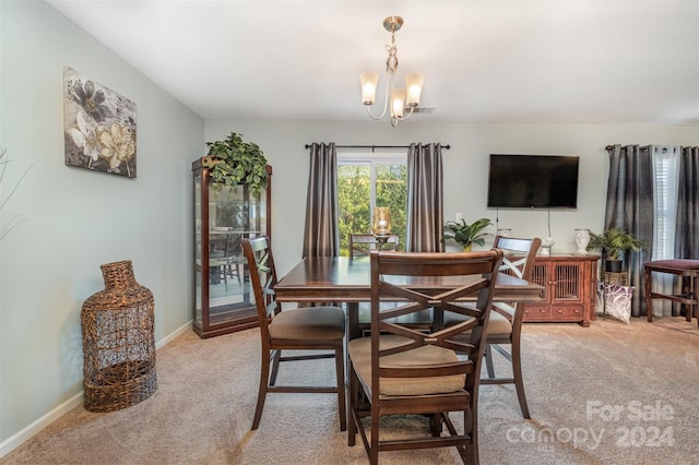 dining room with light colored carpet and a chandelier