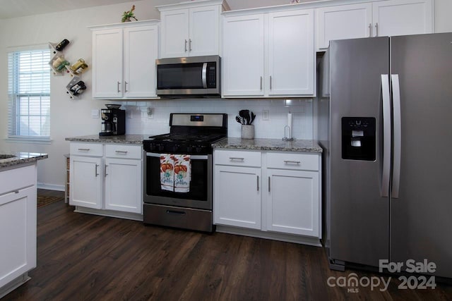 kitchen with light stone counters, white cabinets, dark wood-type flooring, and appliances with stainless steel finishes