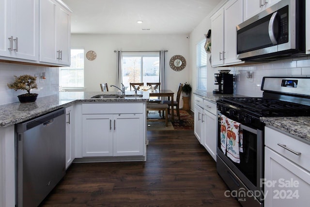 kitchen featuring kitchen peninsula, white cabinets, stainless steel appliances, and dark hardwood / wood-style floors