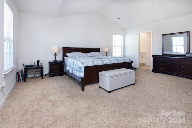 carpeted bedroom with connected bathroom and vaulted ceiling