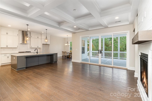 unfurnished living room featuring beam ceiling, dark wood-type flooring, coffered ceiling, and a notable chandelier