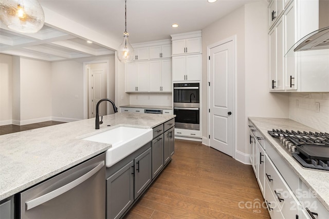 kitchen featuring dark wood-type flooring, white cabinets, sink, hanging light fixtures, and stainless steel appliances