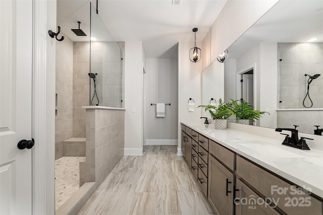 bathroom featuring a walk in shower, double vanity, a sink, and baseboards