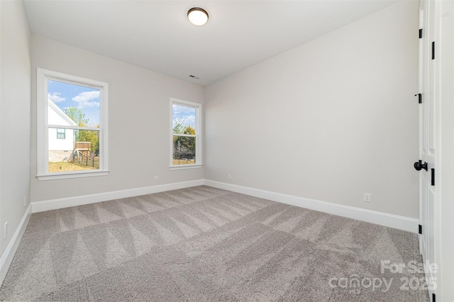 spare room with light colored carpet, visible vents, and baseboards