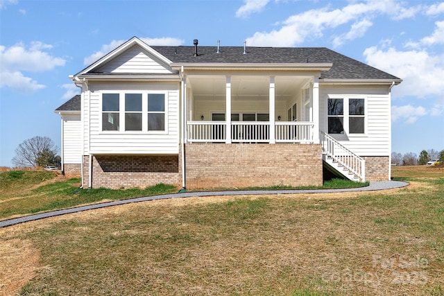 rear view of house with roof with shingles, stairs, a porch, and a yard