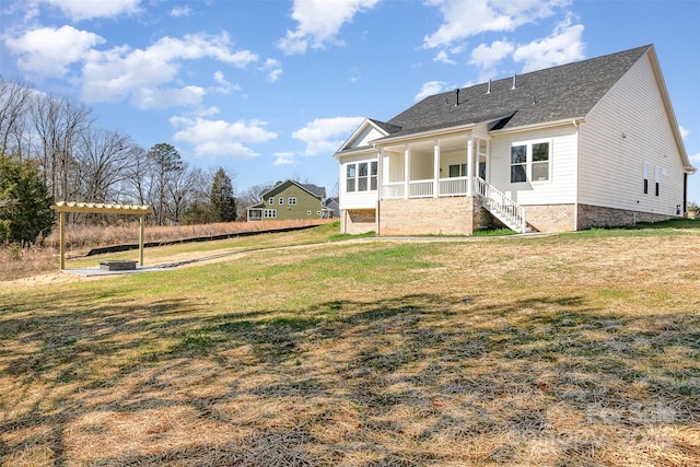 rear view of property featuring covered porch, a pergola, and a yard