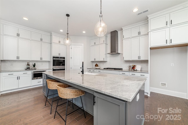 kitchen with visible vents, dobule oven black, white cabinets, wall chimney range hood, and gas cooktop