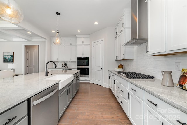 kitchen featuring dark wood-style flooring, gray cabinets, stainless steel appliances, wall chimney range hood, and a sink