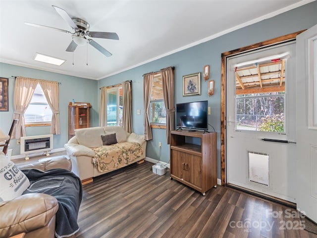 living room with heating unit, dark wood-type flooring, ornamental molding, and ceiling fan