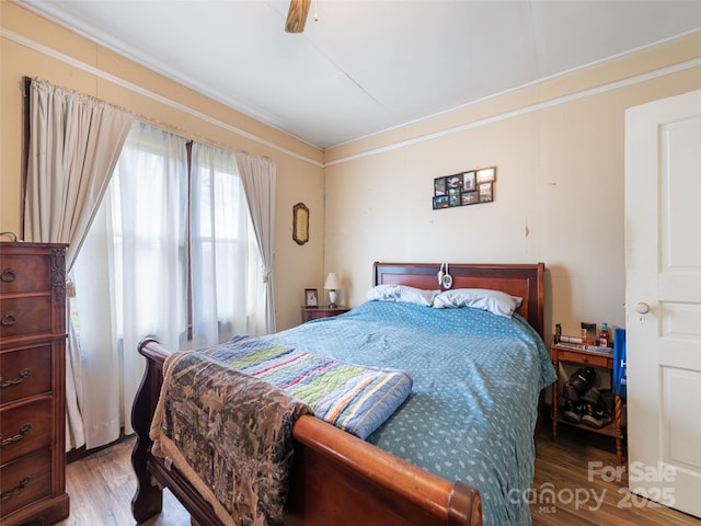 bedroom with wood-type flooring, crown molding, and ceiling fan