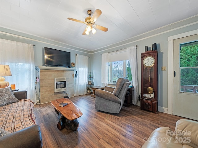 living room with heating unit, dark hardwood / wood-style flooring, ornamental molding, and ceiling fan